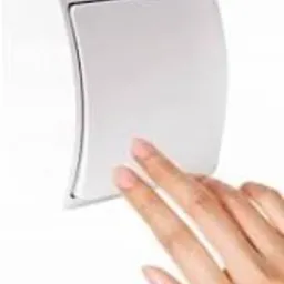 Dłoń naciskająca biały, zaokrąglony włącznik światła na białej ścianie, widok z bliska.