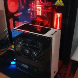 Dwa komputery stacjonarne z oświetleniem LED, jeden z widoczną kartą graficzną Gigabyte i chłodzeniem wodnym z naklejką ostrzegawczą na obudowie, drugi z kartą graficzną MSI, oba na podkładce...