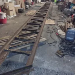 Konstrukcja stalowa w trakcie spawania w warsztacie, widoczne profile i spawane elementy, w tle narzędzia i materiały.