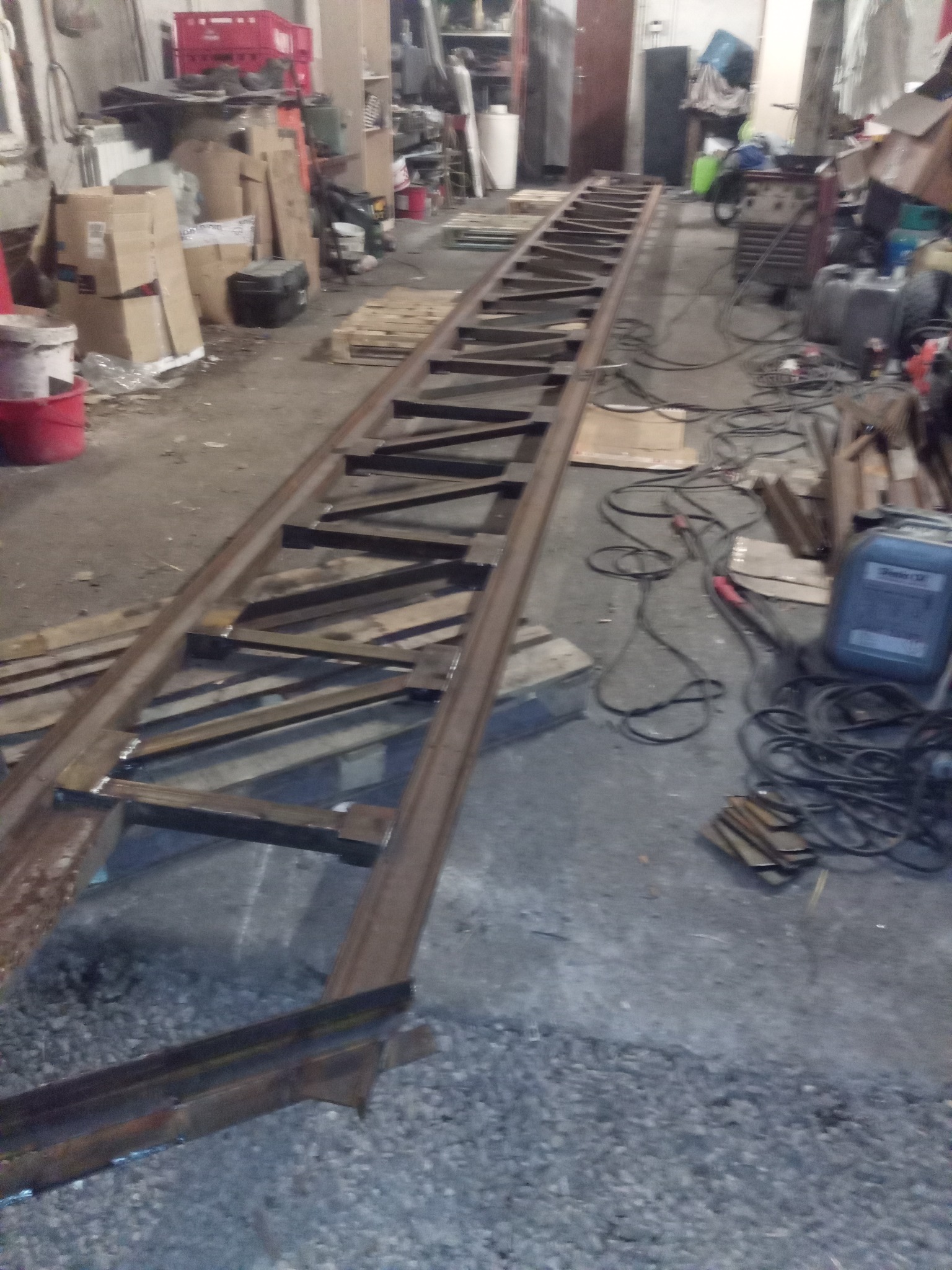 Konstrukcja stalowa w trakcie spawania w warsztacie, widoczne profile i spawane elementy, w tle narzędzia i materiały.