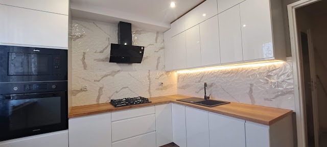 Biała, lśniąca kuchnia w kształcie litery L z drewnianym blatem, czarnym zlewem i płytą gazową, oświetleniem LED pod szafkami oraz piekarnikiem i mikrofalówką w zabudowie.