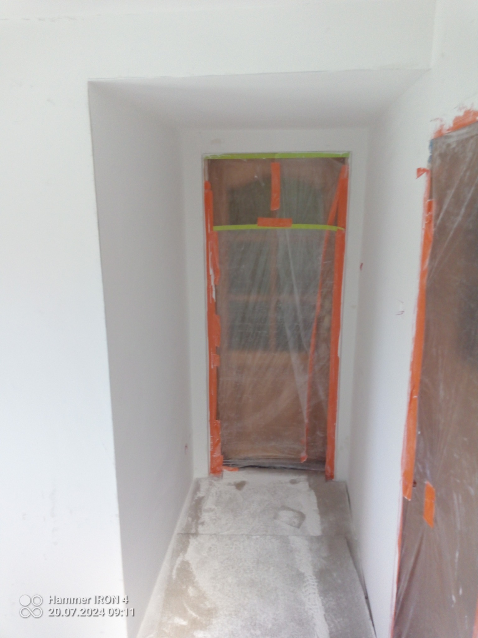 Przygotowanie do malowania: zabezpieczone folią drzwi i ściany wnęki, widoczne ślady farby na podłodze.