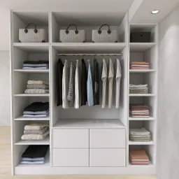 Wnętrze garderoby z białymi półkami, wiszącymi ubraniami i dekoracyjnymi torbami na górze, oświetlone punktowym światłem.