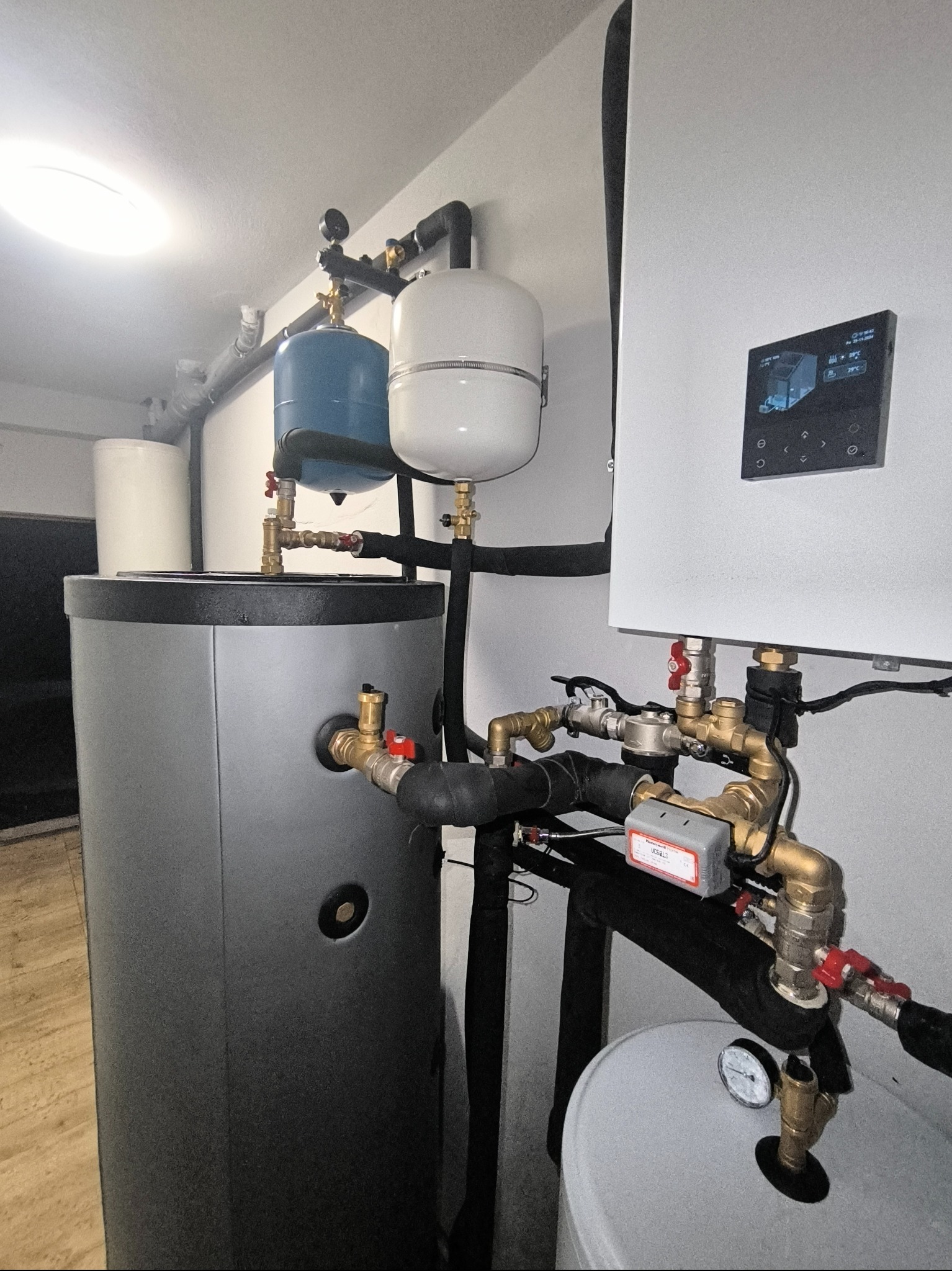 Instalacja centralnego ogrzewania z zbiornikami wyrównawczymi i panelem sterowania w Ratowicach, widoczne liczne rury i zawory.