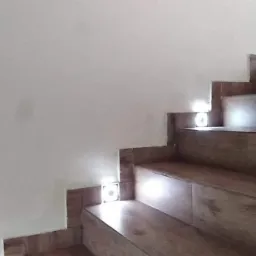 Drewnopodobne płytki na schodach z wbudowanym oświetleniem LED w ścianie, minimalistyczny design.