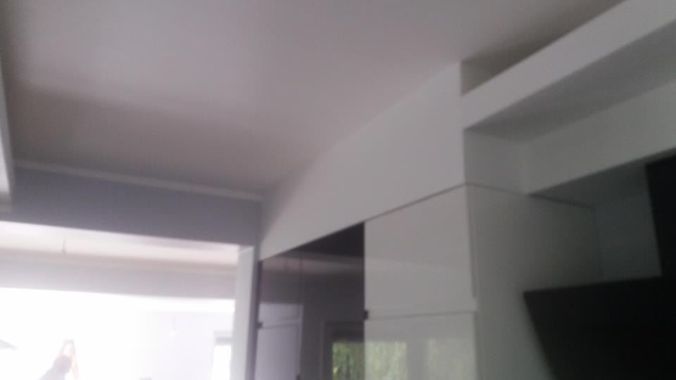 Fragment wnętrza z białym sufitem i zabudową meblową, widoczne łączenie sufitu z elementami konstrukcyjnymi i meblami w nowoczesnym stylu.