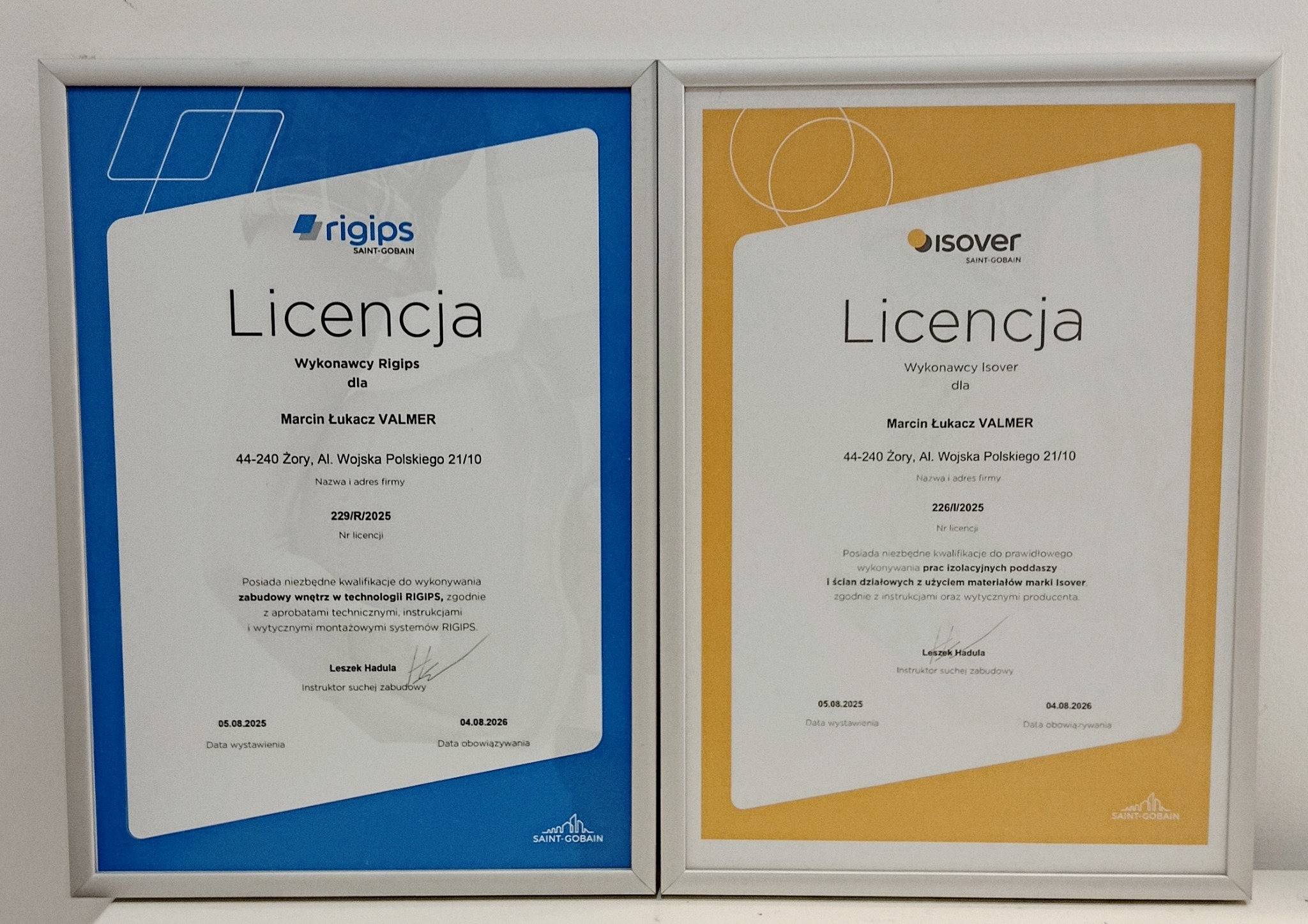 Dwa certyfikaty licencyjne dla wykonawcy Rigips i Isover, oprawione w ramki. Dokumenty potwierdzają kwalifikacje do zabudowy wnętrz i prac izolacyjnych.
