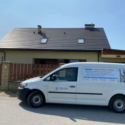 SERWIS OKIEN I DRZWI OKNO-SPEC RAFAŁ TURECKI - Biały samochód serwisowy z reklamą naprawy okien i drzwi zaparkowany przed domem jednorodzinnym z oknami dachowymi.