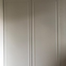 Piotr Mętel - Biała szafa wnękowa z frezowanymi drzwiami i dekoracyjną podłogą z płytek.