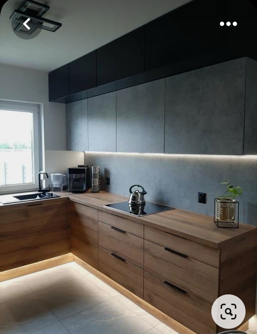 Nowoczesna kuchnia z drewnianymi frontami szafek dolnych i szarymi szafkami górnymi, podświetleniem LED pod szafkami i blatem, czajnik na płycie indukcyjnej.