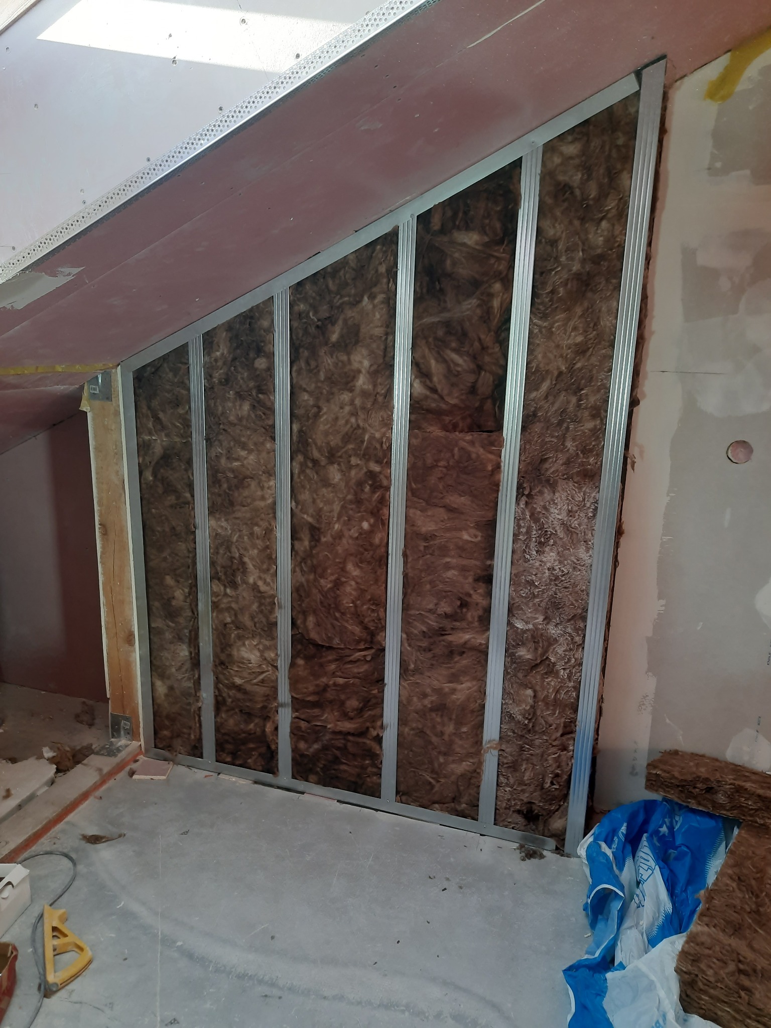 Montaż izolacji wełną mineralną w metalowym stelażu pod skosem na poddaszu w Bydgoszczy, przygotowanie do montażu płyt karton-gips.