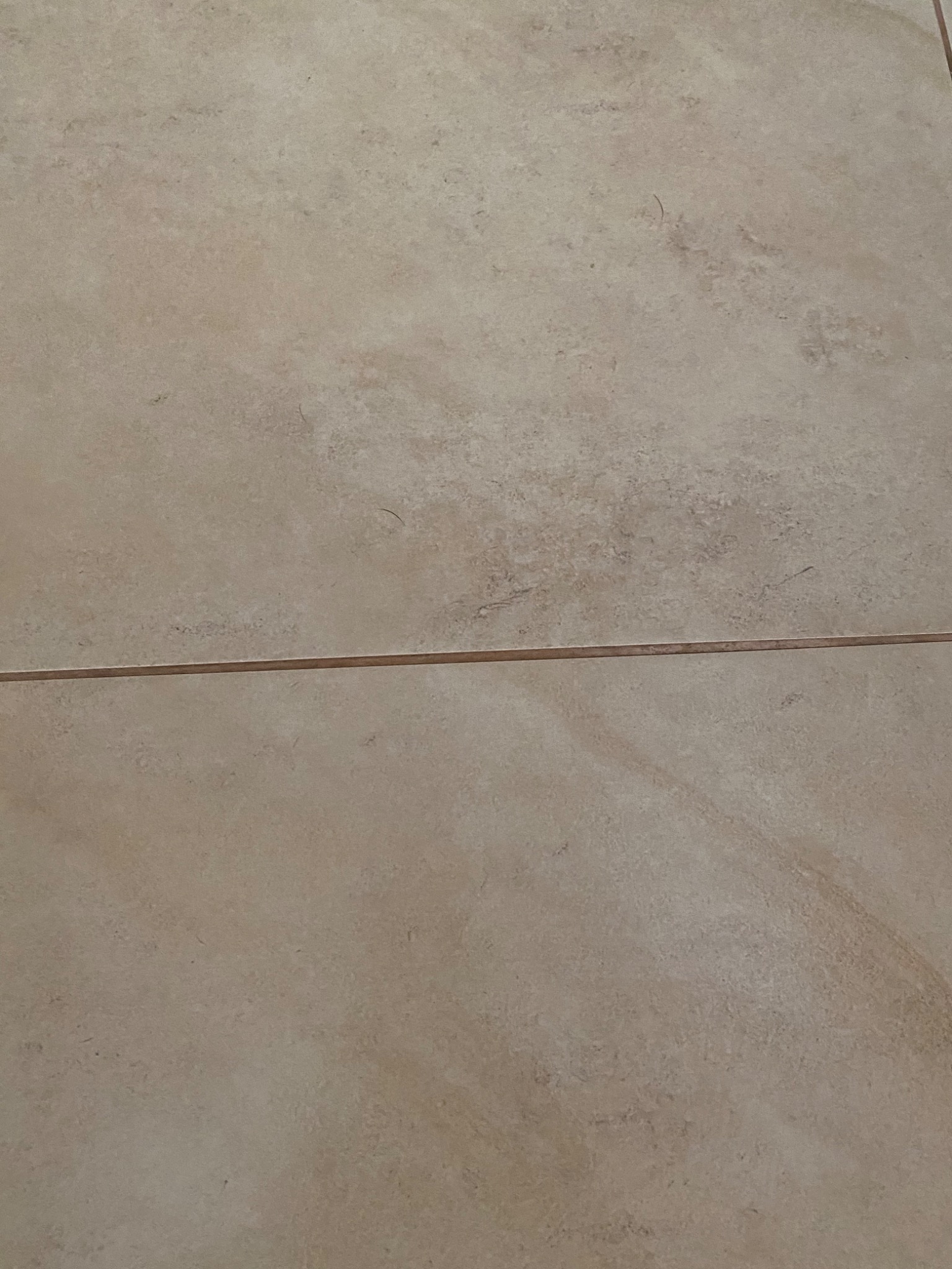 Beżowe, matowe płytki podłogowe z delikatnym wzorem marmurkowym, ułożone z widoczną fugą.