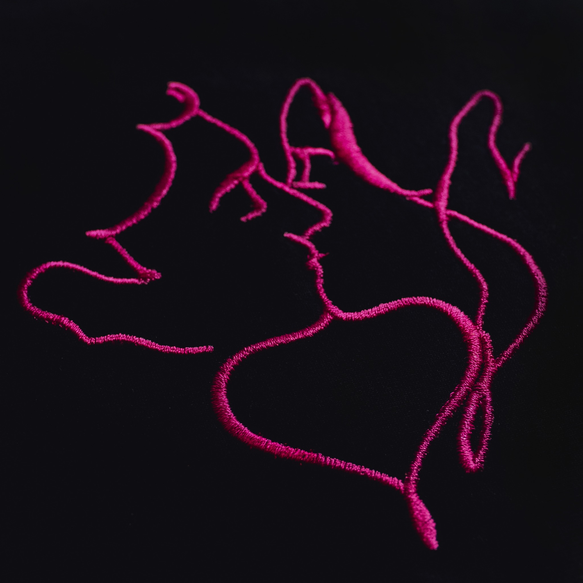 Różowy, abstrakcyjny haft przedstawiający zarys twarzy i serce na czarnym tle.
