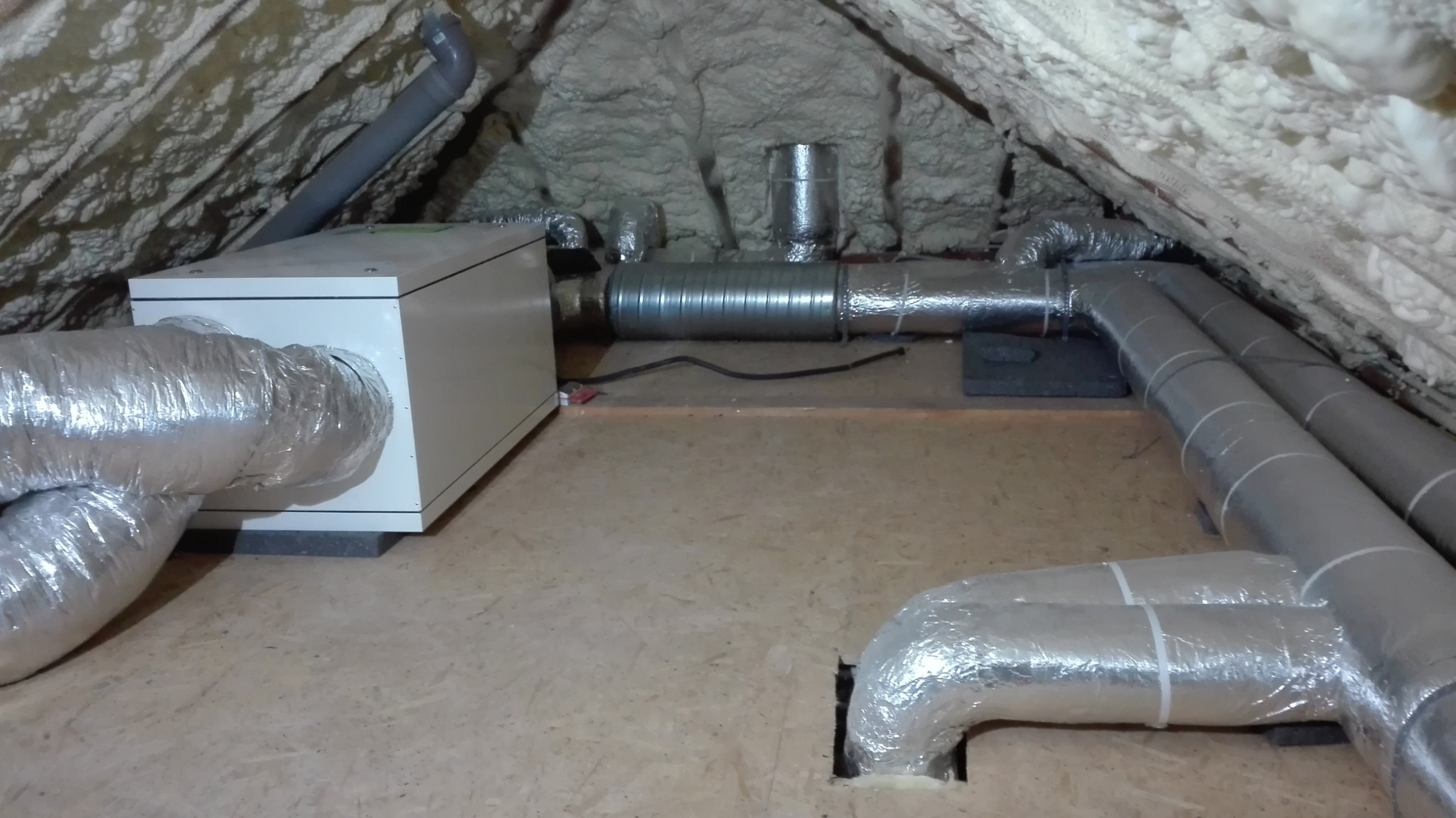 Widok poddasza z zamontowaną centralą wentylacyjną z rurami spiro, całość ocieplona pianą PUR.