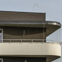 Zabezpieczony siatką balkon apartamentu w nowoczesnym stylu, widok z dołu, srebrna balustrada.