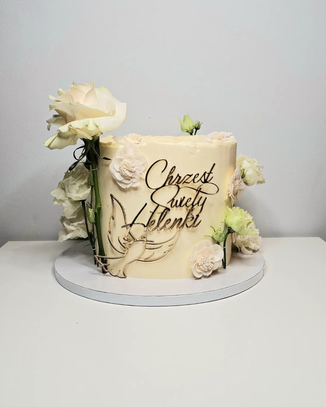 Tort na Chrzest Święty z napisem imienia 'Helenki', zdobiony białymi różami i gołębiem z metalu.