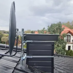 Antena satelitarna zamontowana na dachu domu jednorodzinnego, widok z góry, uchwyty mocujące do komina.