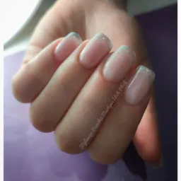 Dłoń z delikatnym, błyszczącym french manicure z użyciem srebrnego brokatu na końcówkach paznokci, na fioletowym tle, z widocznym napisem 'Stylizacja Paznokci Martyna Idzik Płock'.