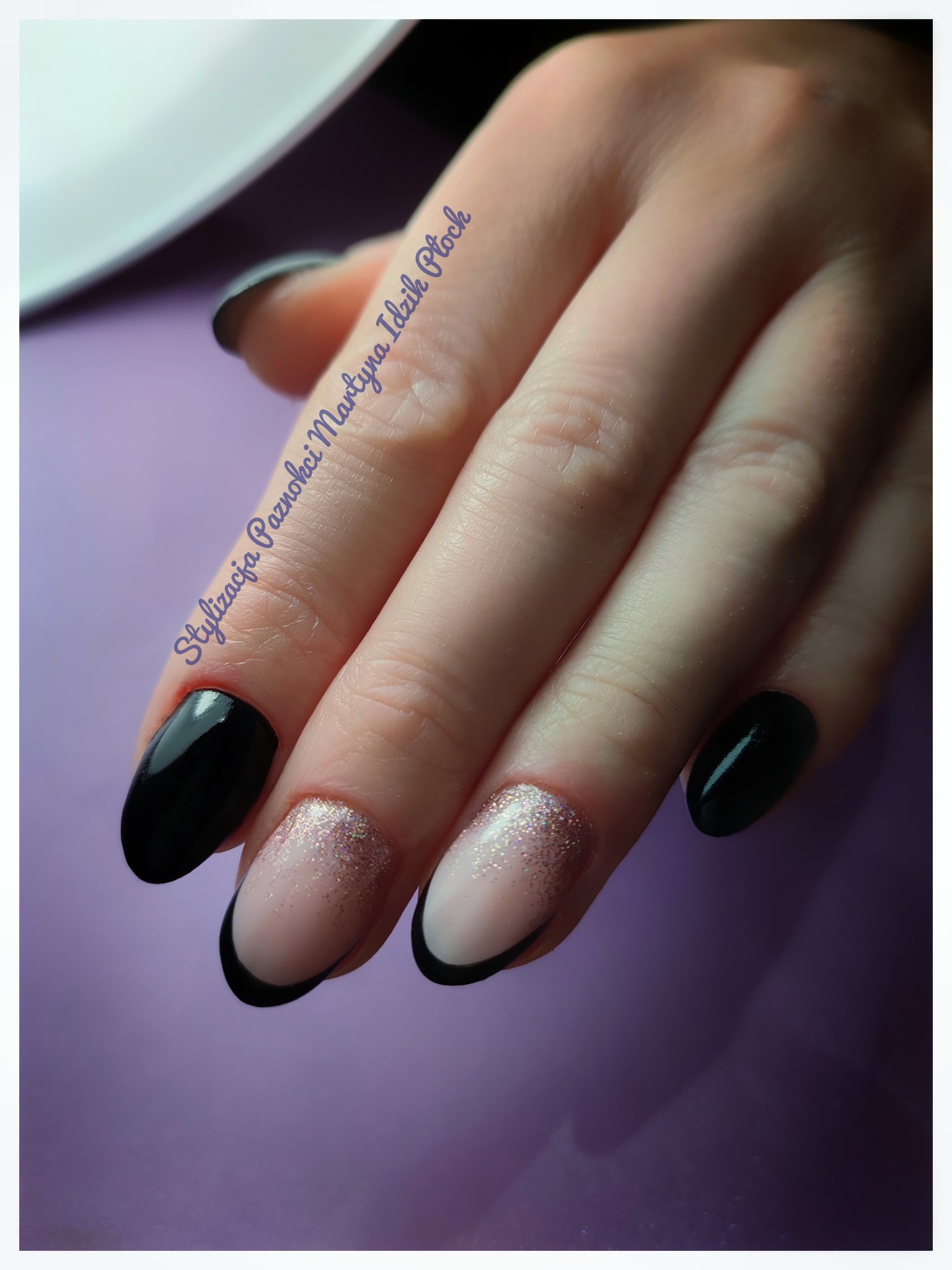 Dłoń z manicure hybrydowym: czarne, błyszczące paznokcie oraz french manicure z brokatowym zdobieniem na dwóch palcach, na fioletowym tle.