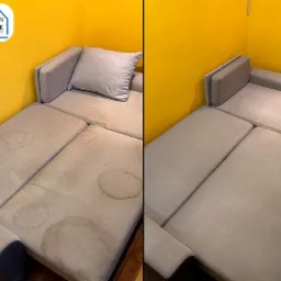 Porównanie: fragment rozłożonej sofy z beżową tapicerką, widoczne plamy przed czyszczeniem po lewej stronie i czysty fragment po prawej, na tle żółtej ściany.