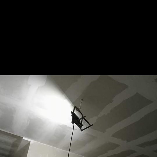 Niedokończony sufit z płyt kartonowo-gipsowych, widoczne łączenia płyt i lampa halogenowa oświetlająca powierzchnię.