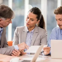 Spotkanie zespołu w Pucku: Cztery osoby analizują dokumenty i dane na laptopie, w tle jasne biuro.