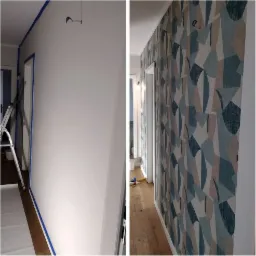 Korytarz: ściana przygotowana do tapetowania z niebieską taśmą maskującą, obok ściana po tapetowaniu w geometryczny wzór w odcieniach niebieskiego i beżu.