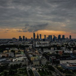Mix Air - Panorama Warszawy o zmierzchu, widok z góry na budynki mieszkalne i drapacze chmur na horyzoncie pod pochmurnym niebem.