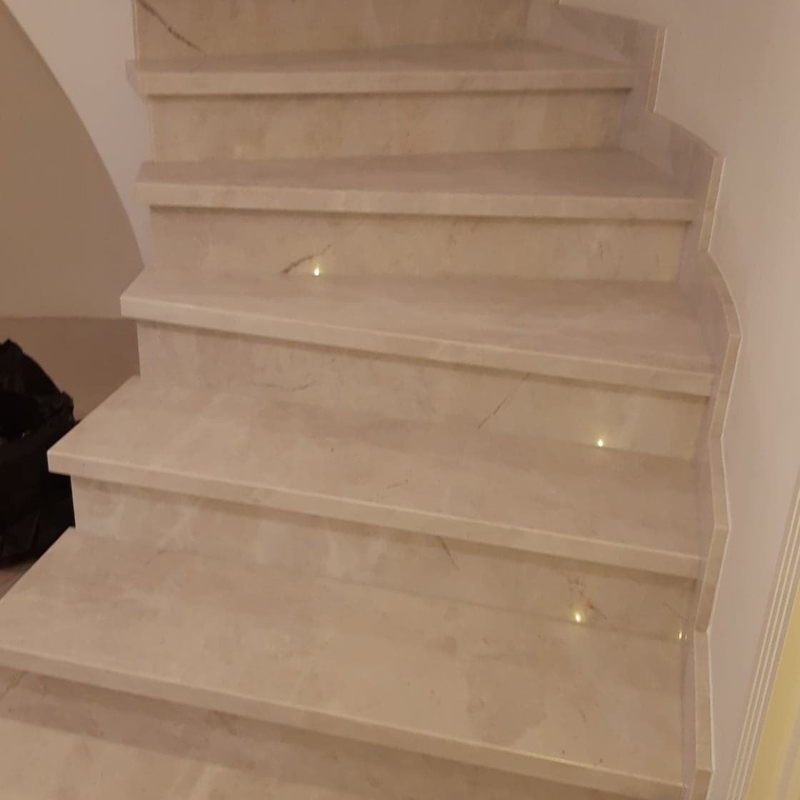 Jasne, wewnętrzne schody z kamienia z delikatnym oświetleniem punktowym w każdym stopniu.