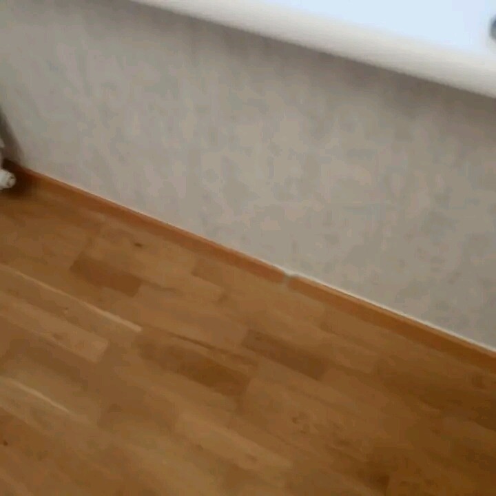 Fragment pokoju po remoncie: świeżo położona drewniana podłoga, jasne tapety z delikatnym wzorem, biała listwa przypodłogowa.