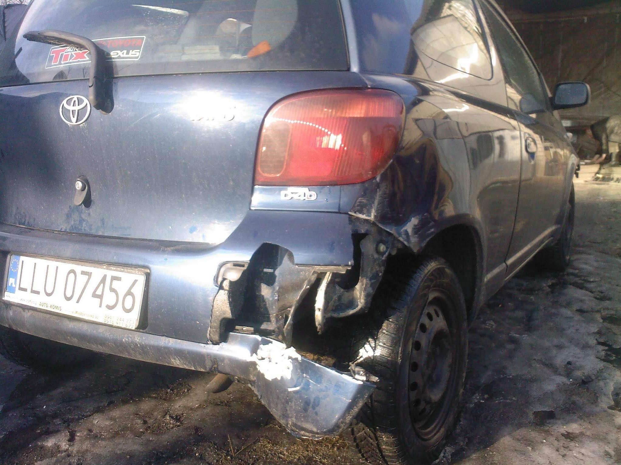 Uszkodzony tył granatowego samochodu Toyota Yaris D4D z widocznym wgnieceniem i brakiem fragmentu zderzaka, tablica rejestracyjna LLU 07456.