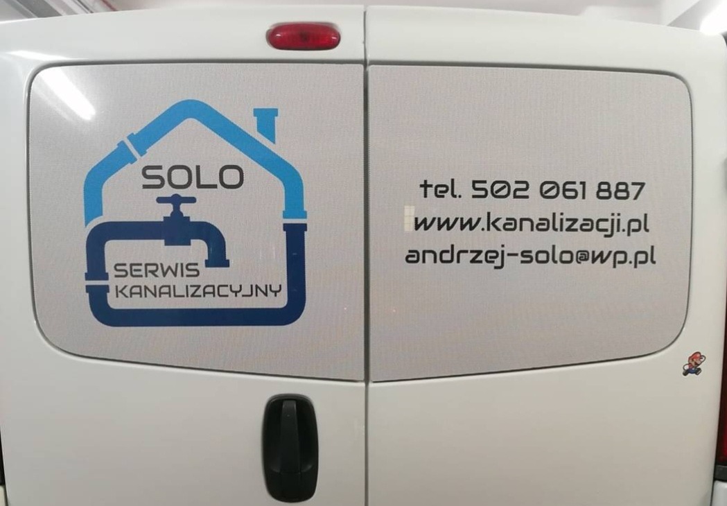 Tylne drzwi białego samochodu dostawczego z naklejoną reklamą firmy SOLO Serwis Kanalizacyjny, zawierającą logo z motywem rur i kranu oraz dane kontaktowe: numer telefonu, adres strony internetowej...