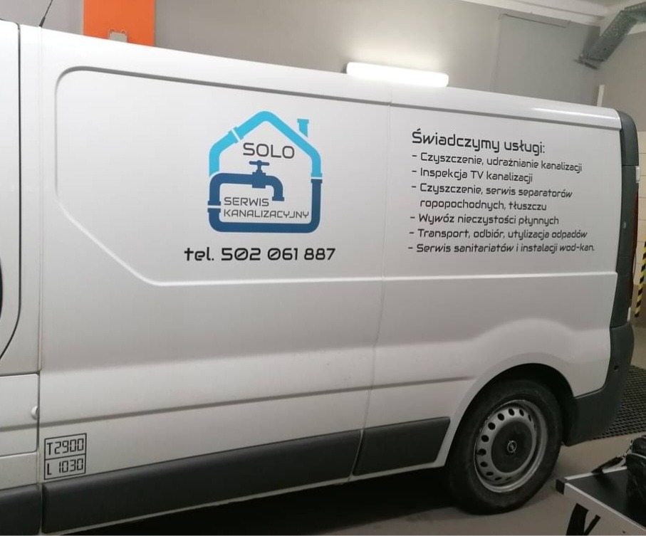 Biały samochód dostawczy z niebieskim logo firmy SOLO Serwis Kanalizacyjny, oferującej czyszczenie kanalizacji, inspekcję TV, serwis separatorów, wywóz nieczystości i serwis sanitariatów.