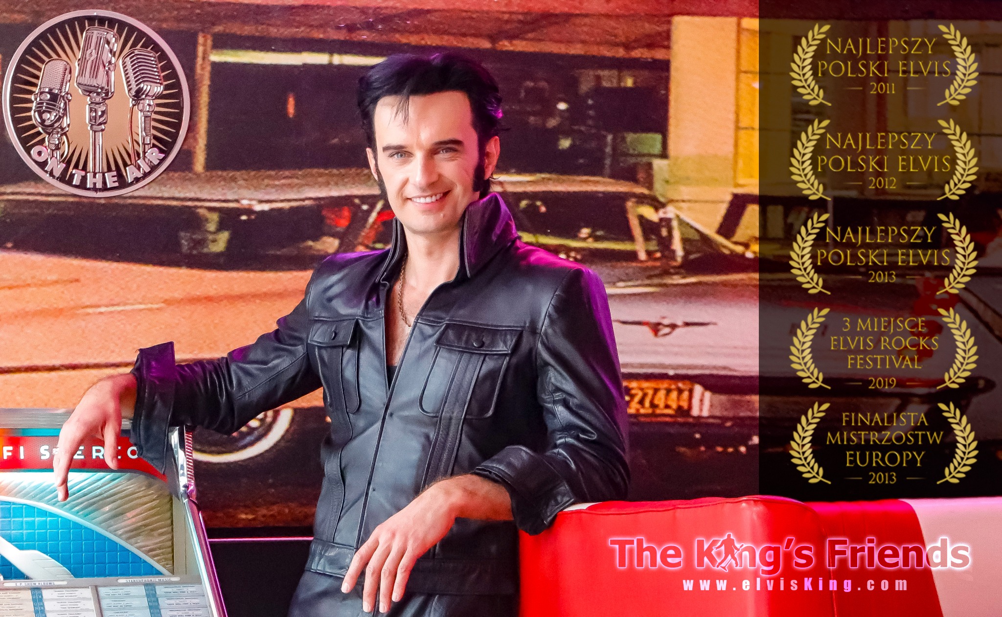 Mężczyzna w czarnym skórzanym stroju, stylizowany na Elvisa Presleya, uśmiecha się, opierając się o automat grający muzykę, z plakatem z nagrodami 'Najlepszy Polski Elvis' w tle.