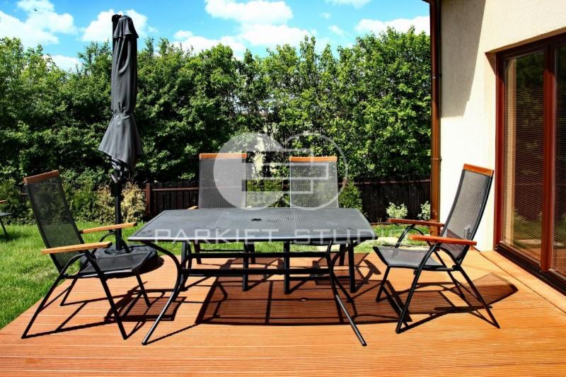 Tarasy z desek Bangkirai: Zestaw mebli ogrodowych na tarasie z desek kompozytowych, widok na trawnik i drzewa.