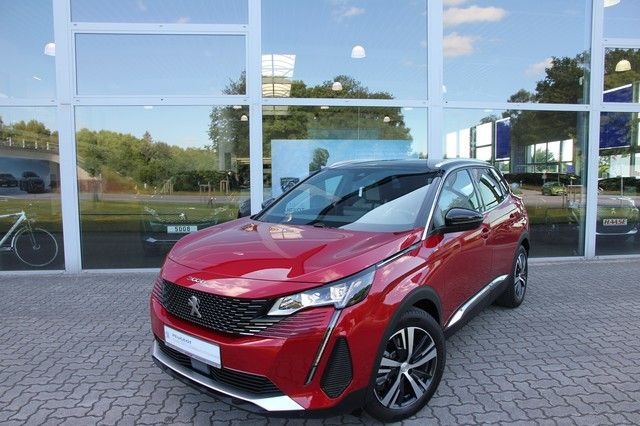 Czerwony samochód Peugeot 3008 SUV zaparkowany przed salonem samochodowym z dużymi oknami, w których odbija się otoczenie.