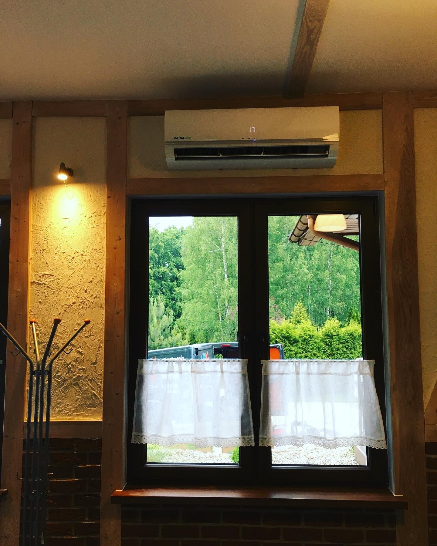 Klimatyzator Kaisai ECO 7 kW zamontowany nad oknem w sali weselnej, widok na zewnątrz przez firanki.