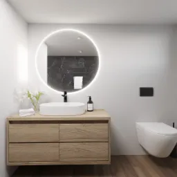 Nowoczesna łazienka z drewnianą szafką pod umywalkę, okrągłym lustrem z podświetleniem LED, wiszącą toaletą i szklanym panelem prysznicowym.