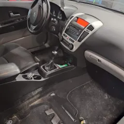 Wnętrze samochodu Kia Ceed przed czyszczeniem w Brzegu, widoczny brudny dywanik i tapicerka, zdemontowane elementy wykończenia.