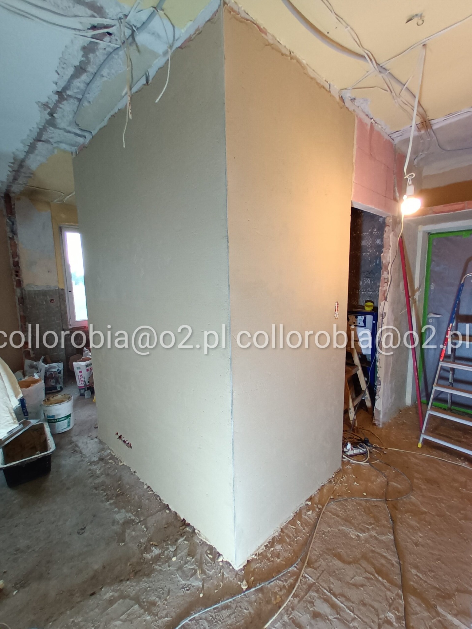Świeżo nałożone tynki i gładzie na ścianach w trakcie remontu mieszkania, widoczne kable elektryczne wystające ze ściany i sufitu, przygotowania do zabudowy GK.