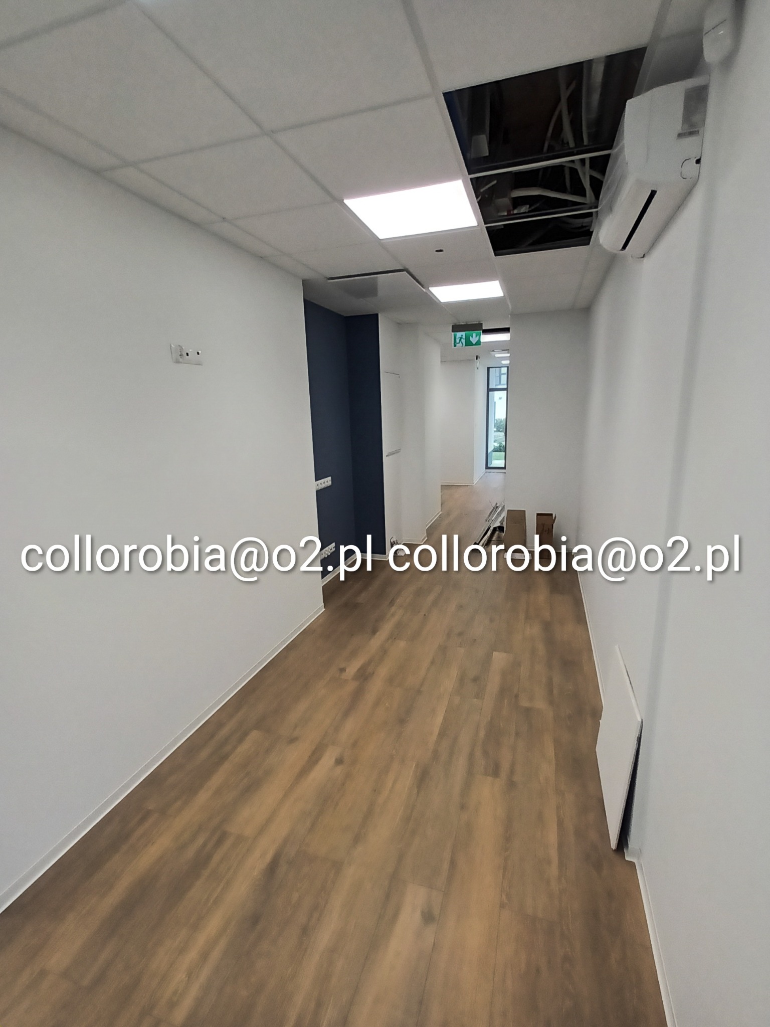 Długi korytarz biurowy po odświeżeniu, z panelami podłogowymi w odcieniach brązu, białymi ścianami i sufitem kasetonowym, widoczne niedokończone prace przy suficie podwieszanym i klimatyzacji.