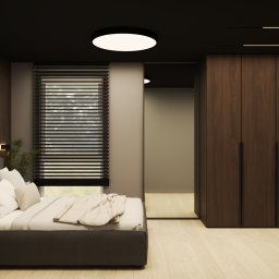 Magda Ciurkot Architektura Wnętrz - Nowoczesna sypialnia z drewnianą ścianą, szarą tapicerowaną ramą łóżka i minimalistycznym oświetleniem. Widok na garderobę i jasną podłogę.