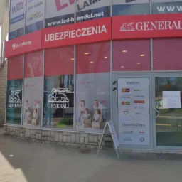 Fasada budynku z biurem firmy ubezpieczeniowej Generali, widoczne logo i napisy Ubezpieczenia, BestMoney, Kredyty oraz naklejki z logo innych firm finansowych na drzwiach.