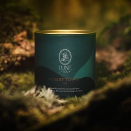 Bohema Pictures - Zielona puszka herbaty LUNE Forest Touch na tle mchu leśnego, złote wieczko, stonowana kolorystyka, naturalne światło.