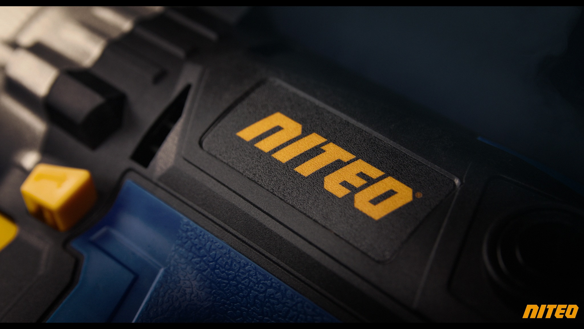 Zbliżenie na czarno-niebieskie urządzenie z żółtym logo Niteo, ukazujące teksturę obudowy i elementy sterujące.