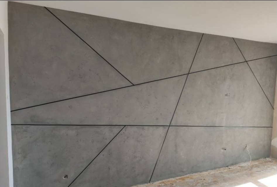 Dekoracyjna ściana z szarego betonu architektonicznego z geometrycznymi podziałami w postaci czarnych listew.