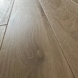 Ułożone panele podłogowe z wyraźną strukturą drewna, widoczne łączenia paneli pod kątem.