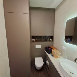 Pro-Home - Nowoczesna łazienka w Warszawie z zabudową meblową w odcieniach brązu, umywalką nablatową i podświetlanym lustrem. Minimalistyczny design i funkcjonalne rozwiązania.