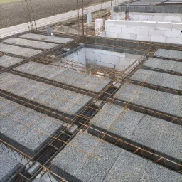 Wznoszenie ścian z betonu komórkowego Ytong, zbrojenie prętami stalowymi, widok z góry na budowę domu jednorodzinnego.