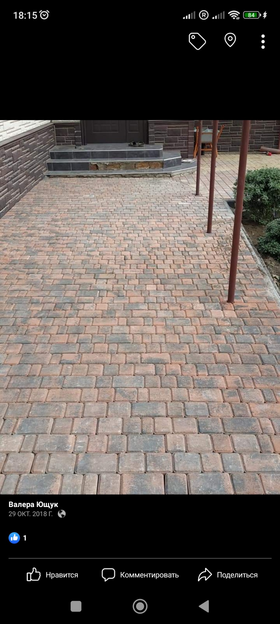 Ułożona kostka brukowa w odcieniach brązu i szarości prowadząca do schodów wejściowych do domu z brązową elewacją.